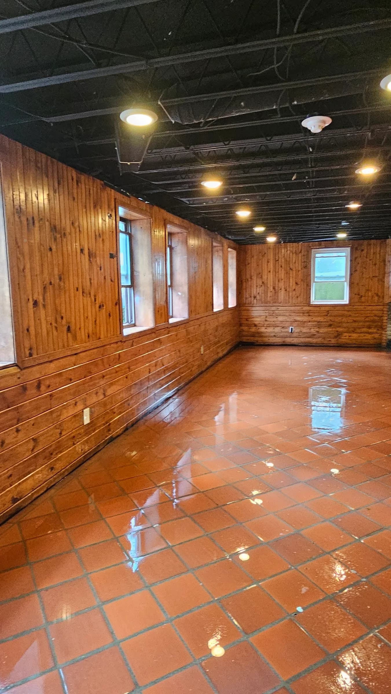 The same wood-paneled room with a clear, reflective tile floor after work